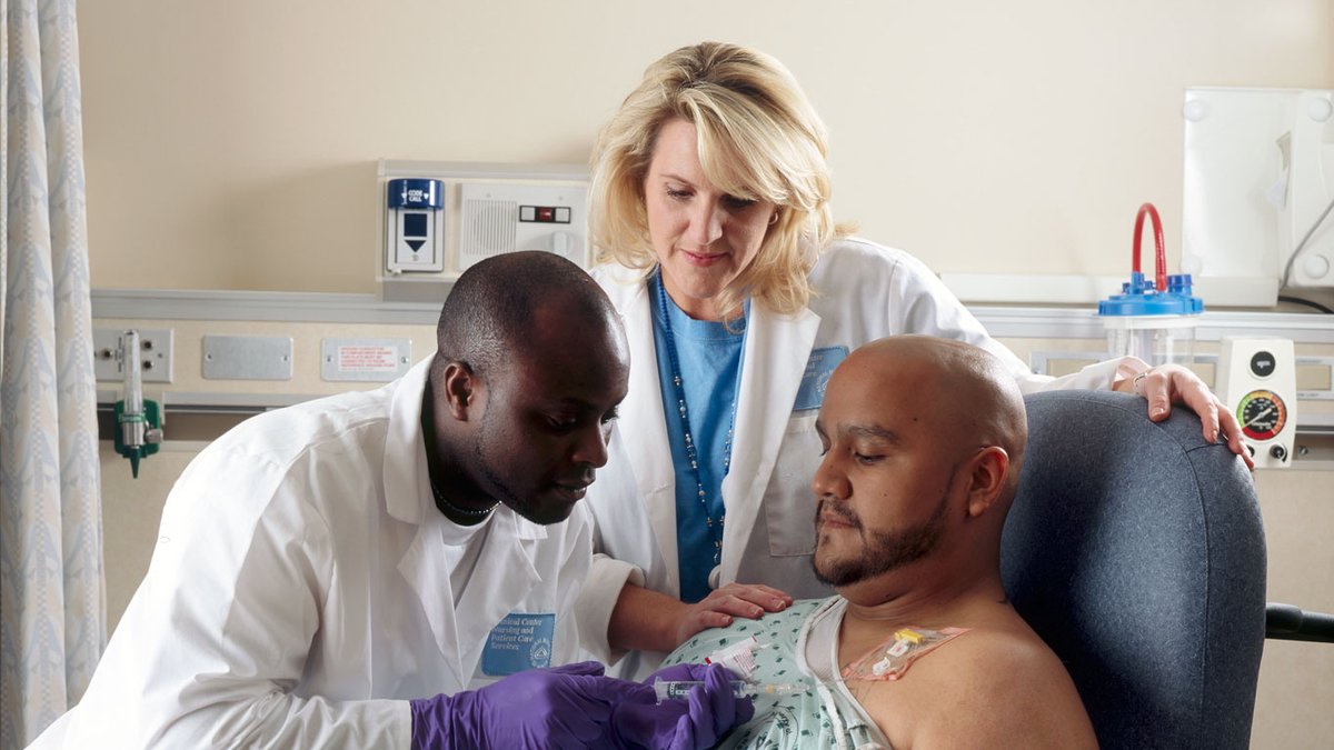 An oncologist consulting with a patient sitting up in a hospital bed
